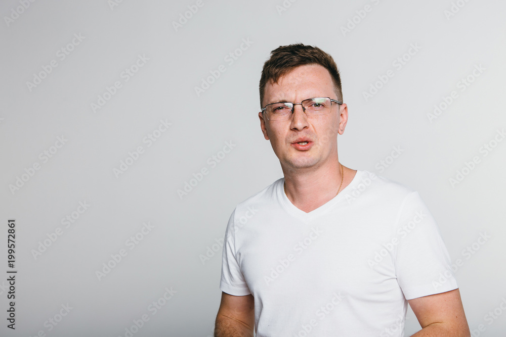 Man disgust while standing against grey background.