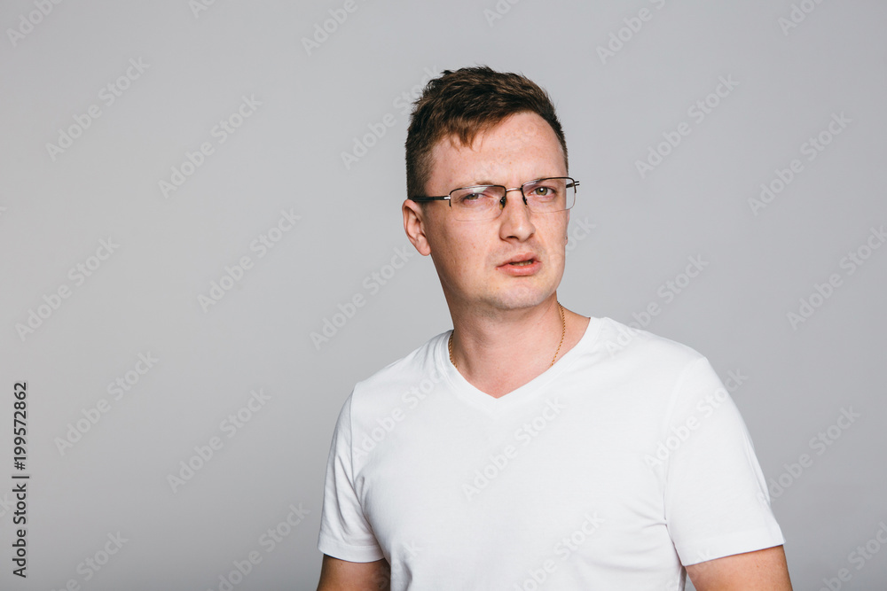 Man disgust while standing against grey background. Man disgust while standing against grey background.