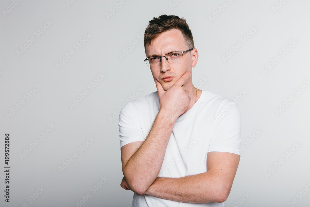 Man thinking and concentrated  while standing against grey background.