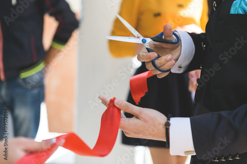 Cutting a red ribbon with scissors, inauguration photo