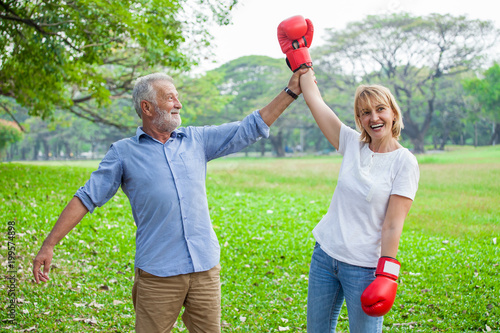 Fotografie Happy funny senior couple boxer man and woman with red gloves in park