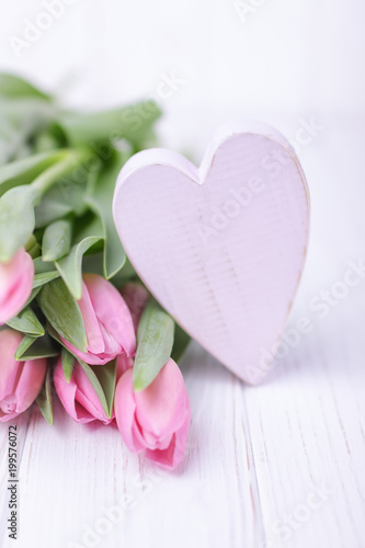Pink tulips and pink heart on a wooden background. Happy Valentine's Day. Free space