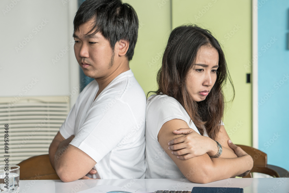 Unhappy couple not talking after an argument at home. depressed woman sitting on the sofa and sad man sitting on the table looking at girlfriend. selective focus on woman face. Unhappy couple not talking after an argument at home. depressed woman sitting on the sofa and sad man sitting on the table looking at girlfriend. selective focus on woman face.