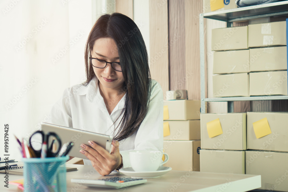 Happy pretty asian business woman entrepreneur smiling and working on the desk in his home. Successful young businessman in e commerce manage his order to sent parcel by post at home. Happy pretty asian business woman entrepreneur smiling and working on the desk in his home. Successful young businessman in e commerce manage his order to sent parcel by post at home.