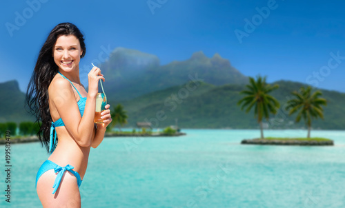 summer holidays, vacation and beach concept - smiling woman in bikini with bottle of non alcoholic drink over bora bora island beach background
