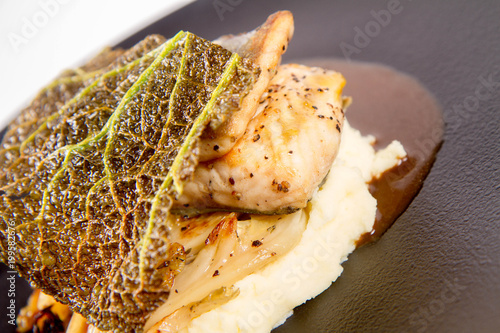 Sturgeon, savoy cabbage, mushrooms broth, mashed potato with butter on a plate on a white background