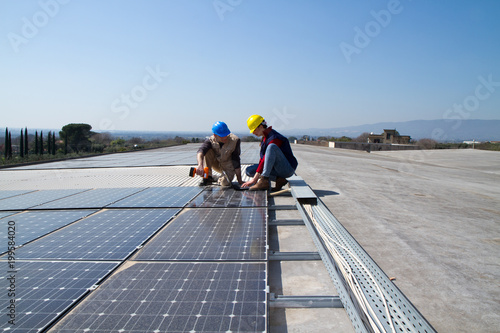 Obraz na płótnie young engineer girl and an elderly skilled worker fitting a photovoltaic plant w salonie