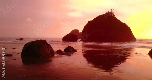 Wide Aerial of Man Climbing Rock on the Beach photo