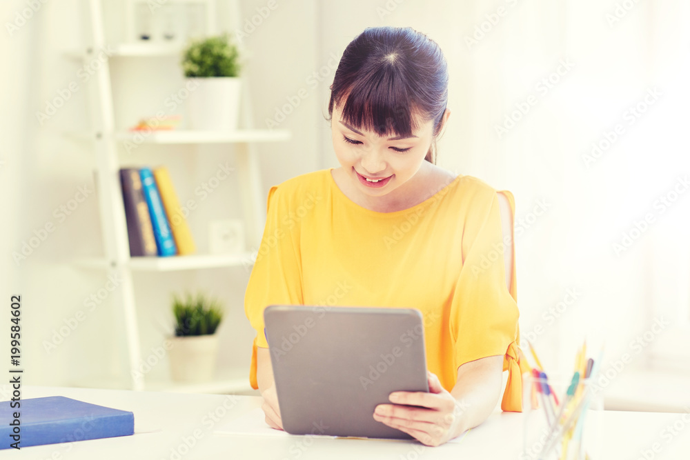 people, education, high school and learning concept - happy asian young woman student with tablet pc computer, book and notepad writing at home people, education, high school and learning concept - happy asian young woman student with tablet pc computer, book and notepad writing at home