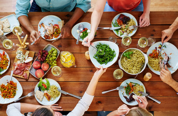 eating, food and leisure concept - group of people sharing green beans at table