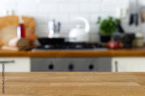 Empty wood counter in front of out of focus home kitchen background.