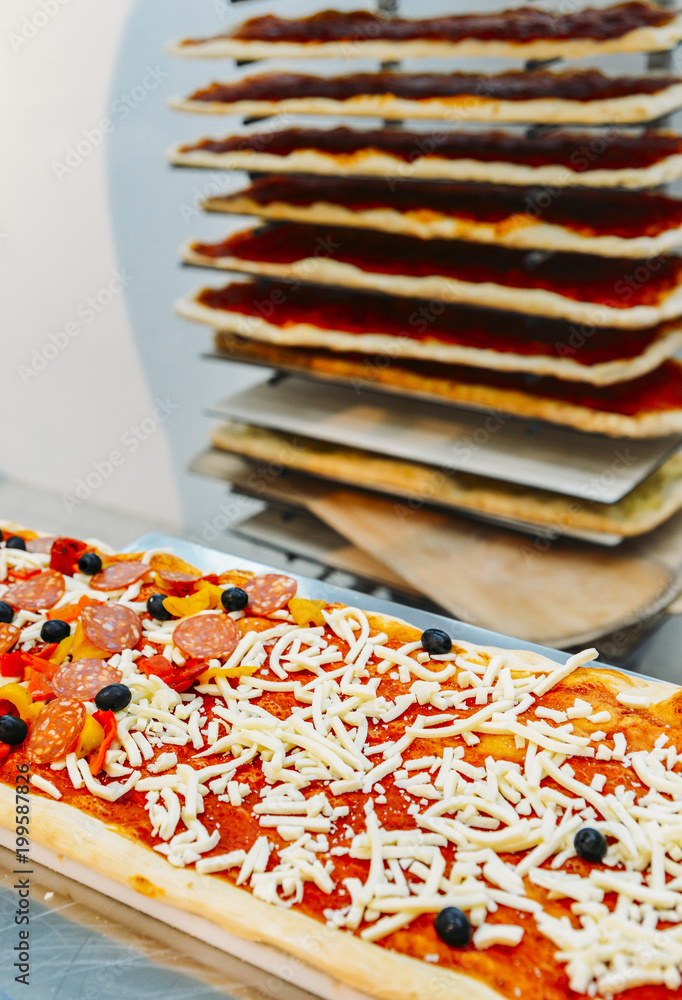 Fototapeta premium Uncooked rectangular Roman style pizza with salami topping