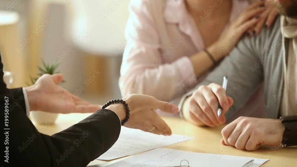 Couple sign mortgage contract, put signature on sale purchase rental agreement, handshaking realtor at meeting with estate agent, satisfied customers buy property, get keys of new home, close up view Couple sign mortgage contract, put signature on sale purchase rental agreement, handshaking realtor at meeting with estate agent, satisfied customers buy property, get keys of new home, close up view