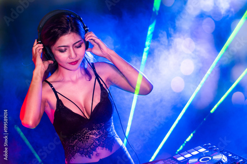 Sexy asian Dj mixing music in the club party. female disc jockey on turntable in nightclub enjoying mixing sound music for entertain clients.