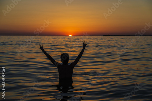 Teenager boy bathing in the sea at sunset in Sicily