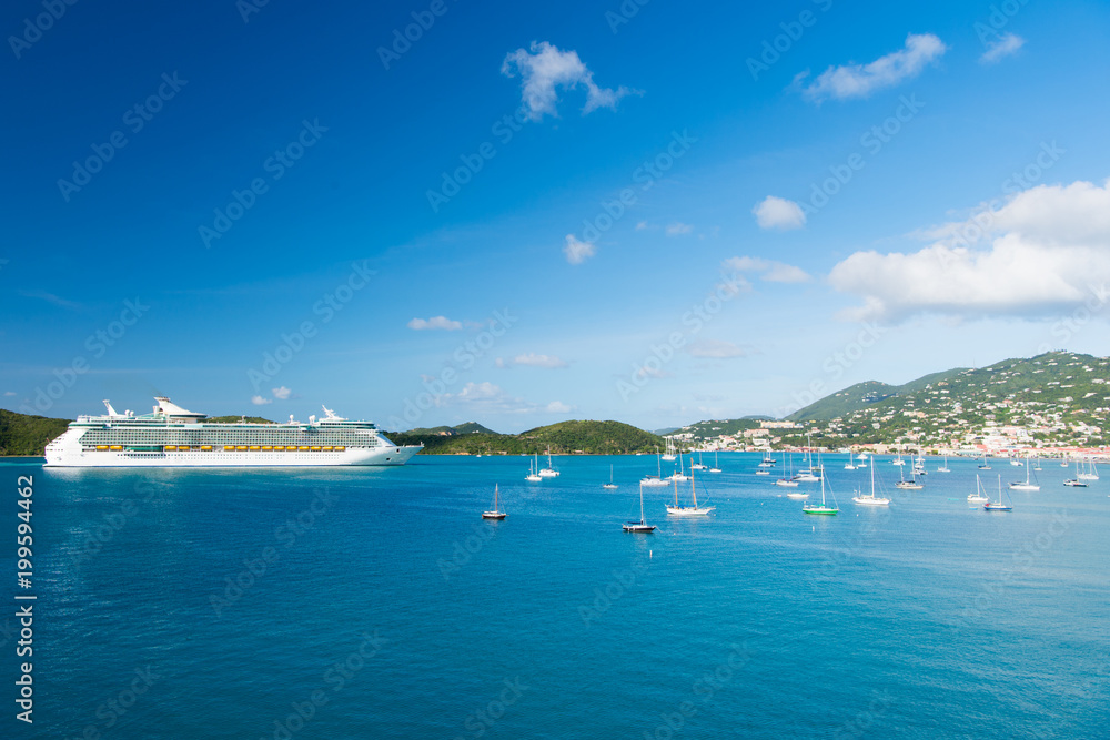 Obraz premium St.Thomas, British virgin island cruise ship and yachts at seaside. Ocean liner in blue sea on sunny sky. Water transport and vessel. Travel by sea, wanderlust. Vacation on island
