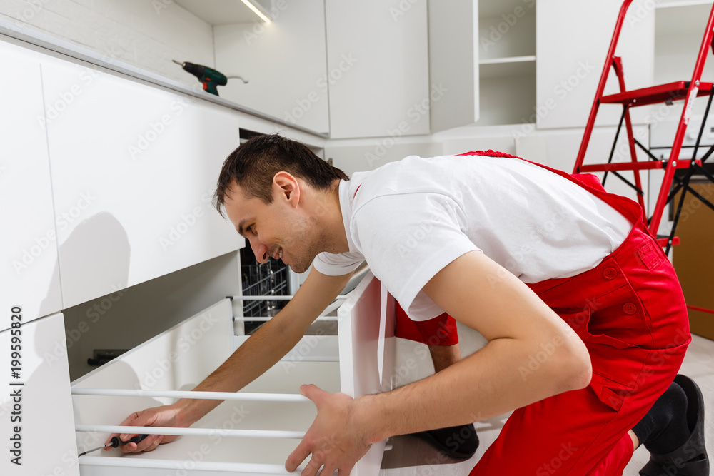 Obraz premium Handyman putting up a shelf in the kitchen