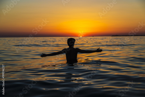 Teenager boy bathing on a beach at sunset in Sicily