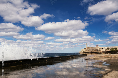 Promenade of the Malecon of Havana, Morro Castle and its lighthouse with crashing waves © Angelo D'Amico