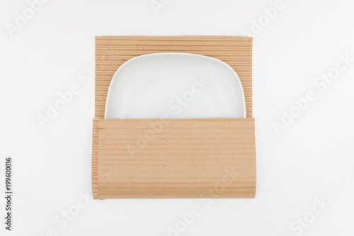  White plate in kraft paper on white background. Concept of storage, feeling safe, protect, relocation. photo