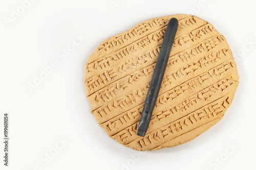 Ancient type of Akkad empire style cuneiform writing in brown clay with writing tools