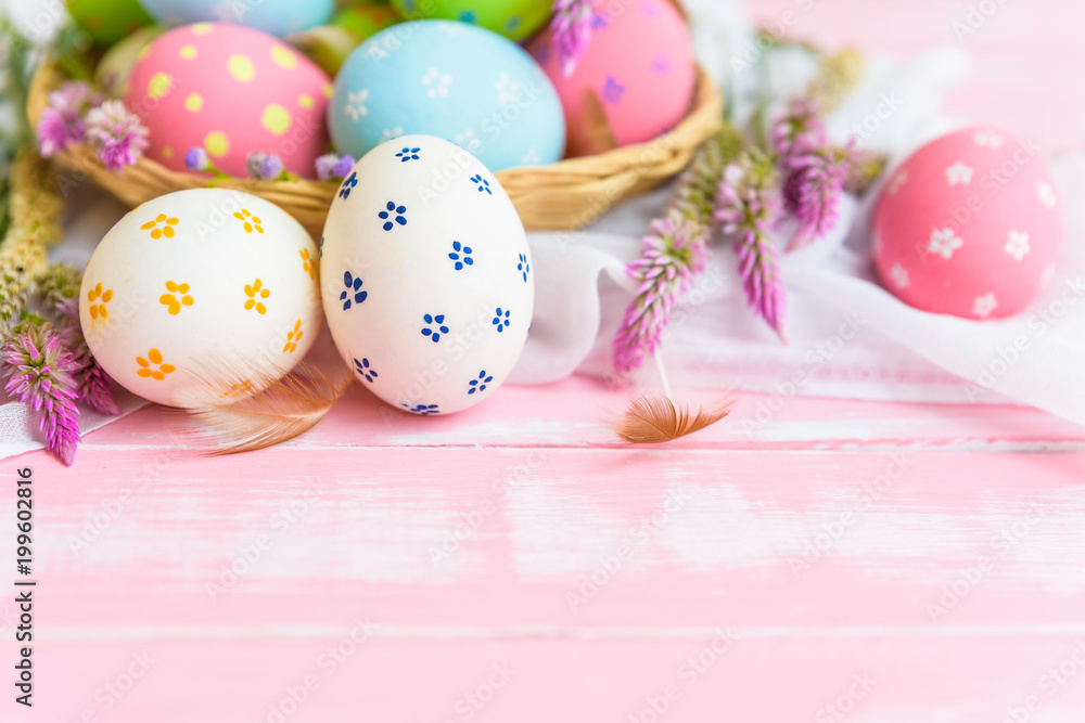 Fototapeta premium Happy easter! Colorful of Easter eggs in nest with paper star, flower and Feather on pastel color bright pink and white wooden background.