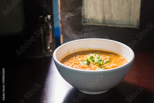 Instant noodles Tom Yum Koong with egg and celery on wood table,hot bowl