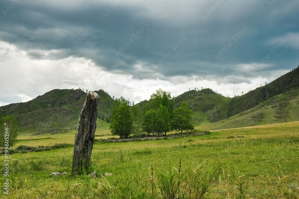Idol stone on the meadow surrounded by mountains. Altai, Siberia, Russia