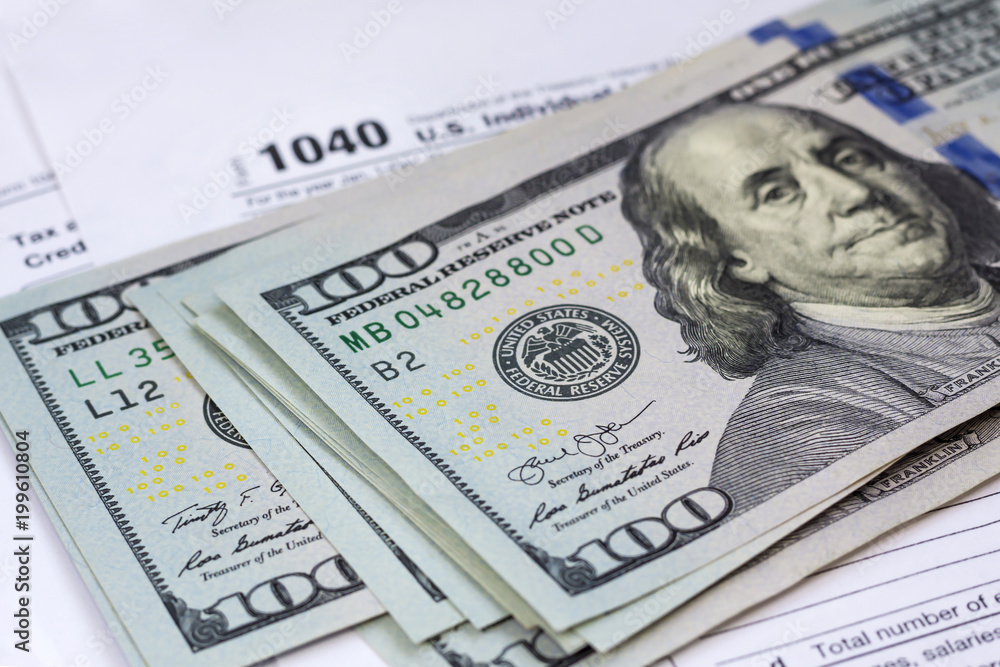 100 dollar bills on 1040 Individual Income Tax Return Form background, close up 100 dollar bills on 1040 Individual Income Tax Return Form background, close up