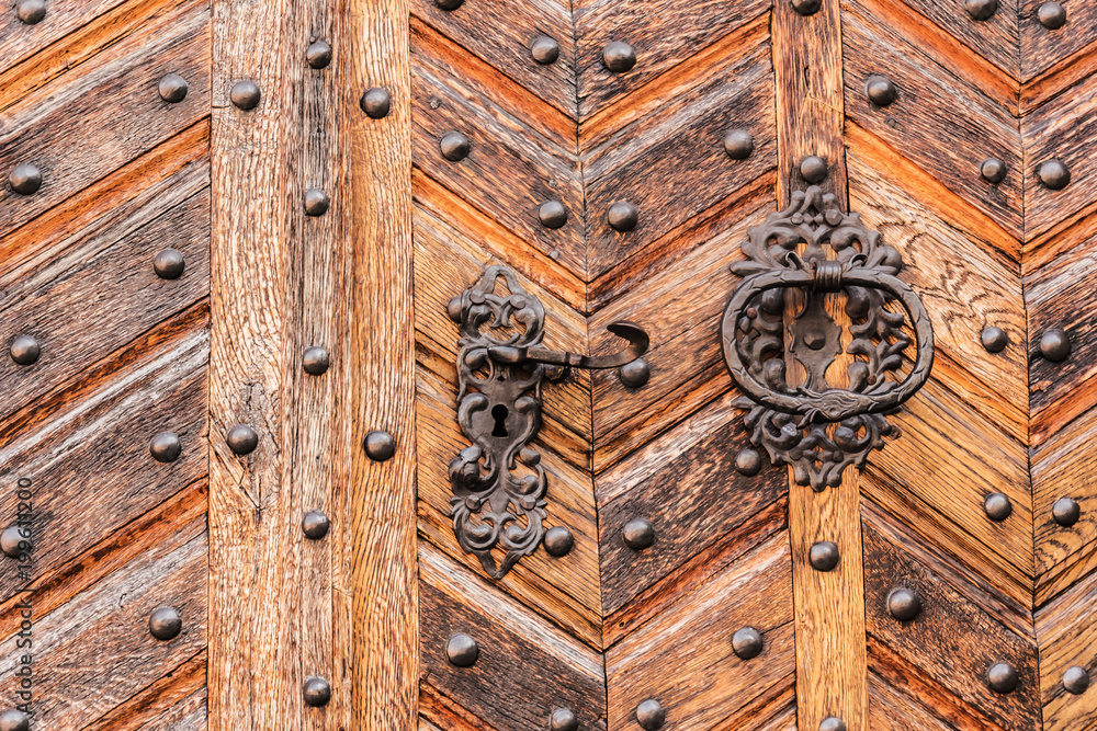 Old wooden door with metal decorative  lock and door knocker.