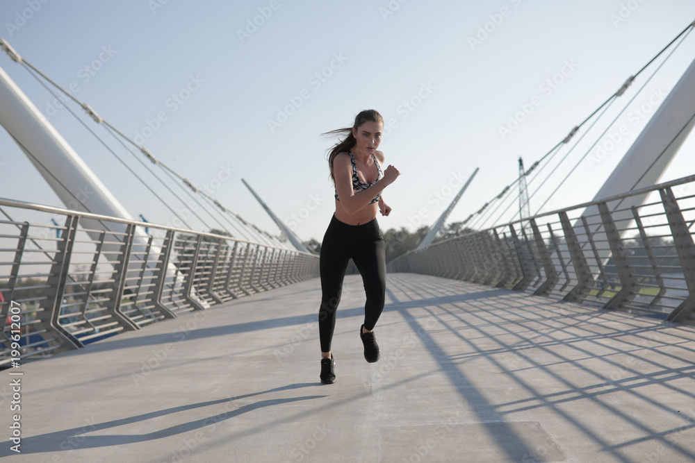 Active woman runner jogging across bridge, outdoors running, sport and healthy lifestyle concept.