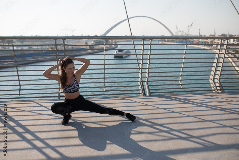 Sports woman doing stretching exercises on a bridge. Sports woman doing stretching exercises on a bridge.