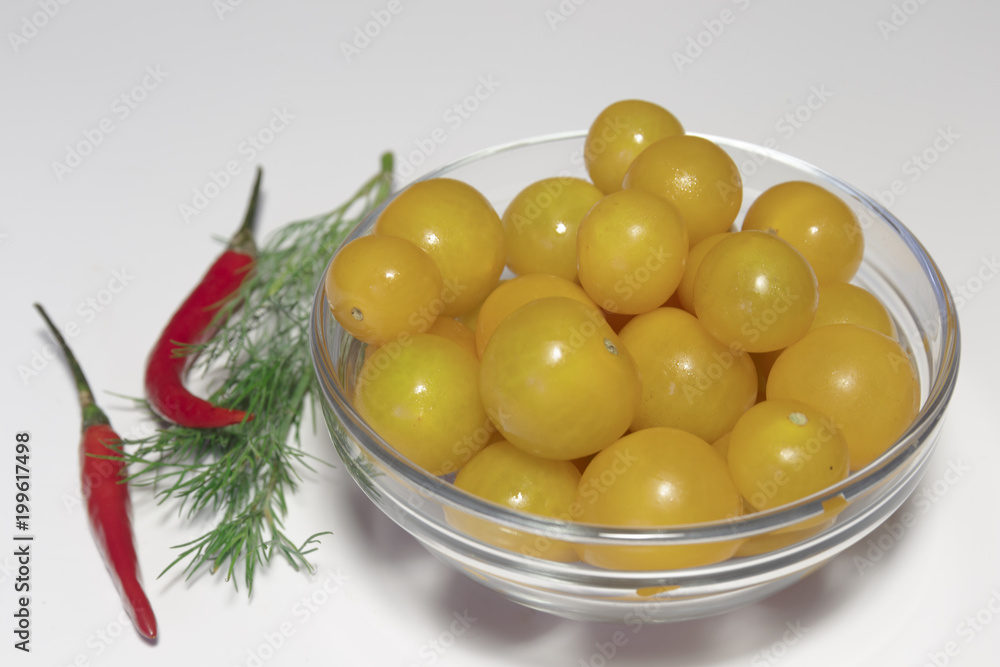 Raw yellow cherry tomatoes in the glass dish closeup, ready to eat, isolated on white, vegan food. Raw yellow cherry tomatoes in the glass dish closeup, ready to eat, isolated on white, vegan food.