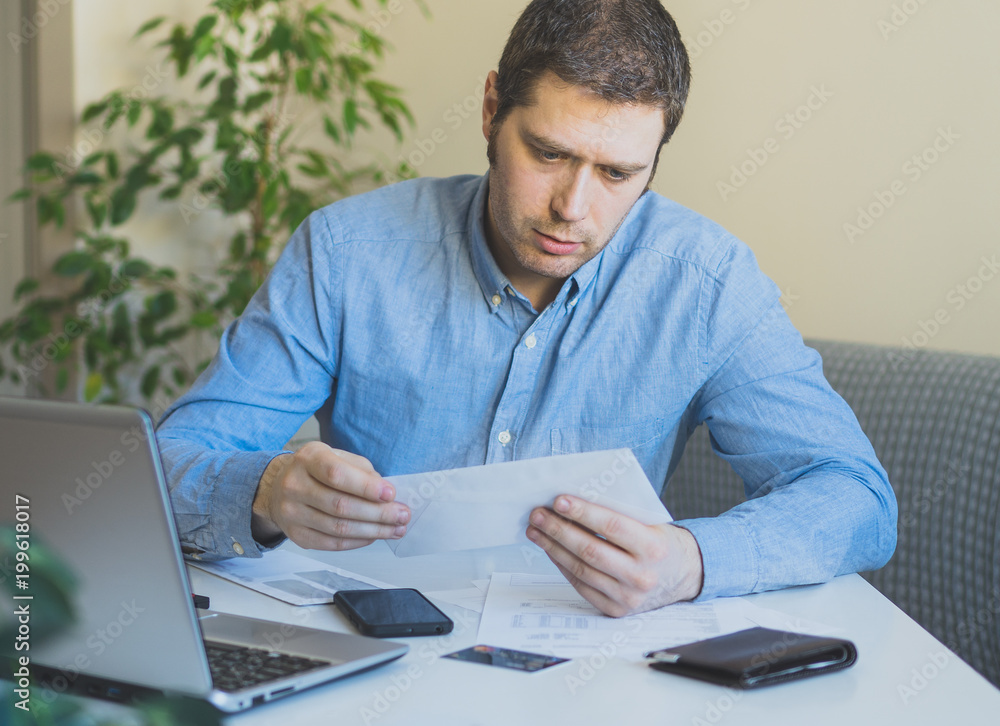Fototapeta premium Man looking at his monthly bills at home.