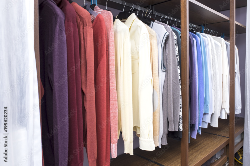 Men's clothes on hangers hanging in a dressing room.