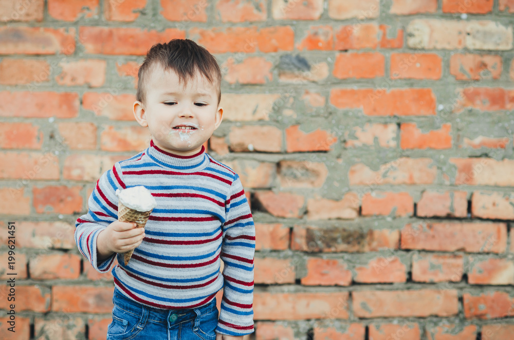 little cute boy boy boy three years eating ice cream very appetizing on brick wall background little cute boy boy boy three years eating ice cream very appetizing on brick wall background