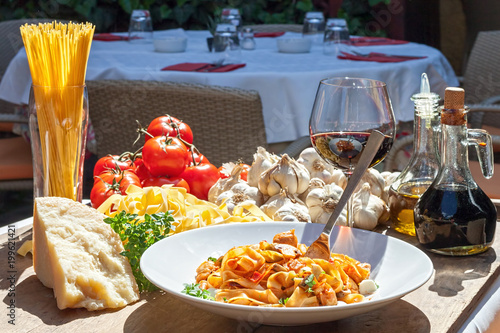 sunlit plate of Italian pasta with basic ingredients around