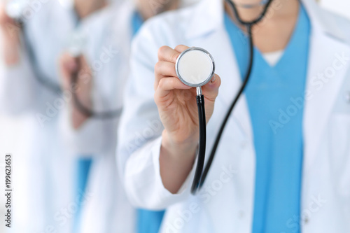 Groupe of medicine doctors hold stethoscope head closeup. Physicians ready to examine and help patient. Medical help and insurance in health care, best treatment concept. Photo for advertisement