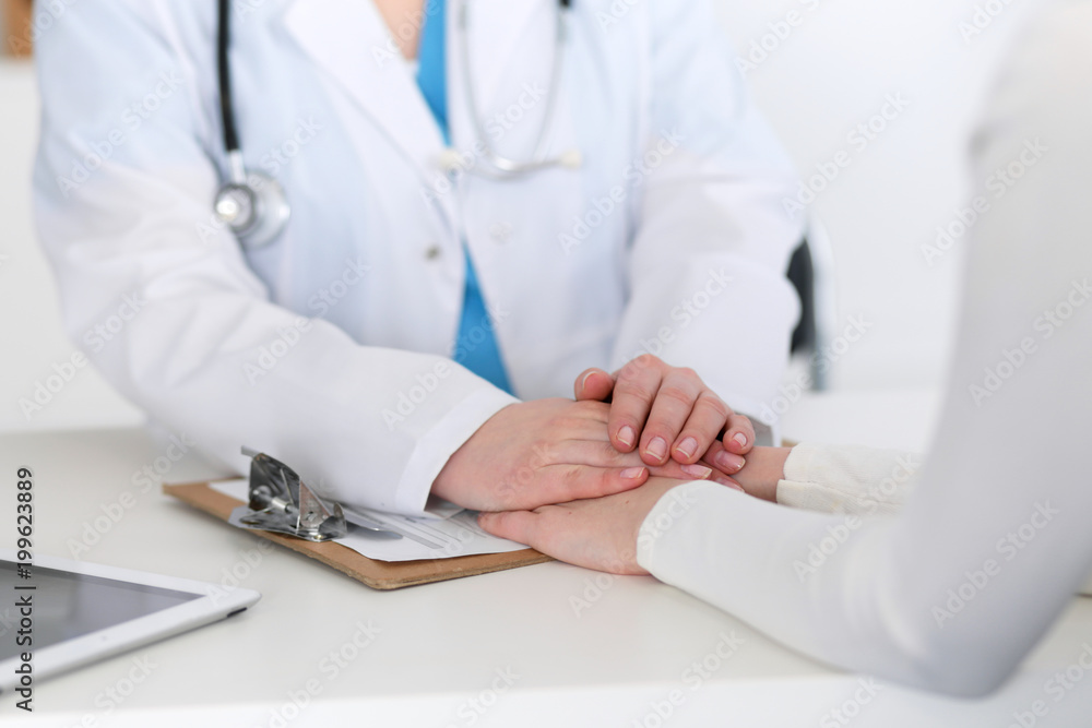 Medicine doctor hand reassuring her female patient closeup. Medicine, comforting and trusting concept in health care Medicine doctor hand reassuring her female patient closeup. Medicine, comforting and trusting concept in health care