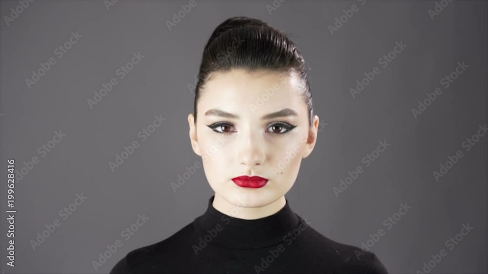 Portrait of a beautiful sexy girl. Fashion model posing on a dark background for studio photo shoot. Slowmo. Close up. Red lips Portrait of a beautiful sexy girl. Fashion model posing on a dark background for studio photo shoot. Slowmo. Close up. Red lips