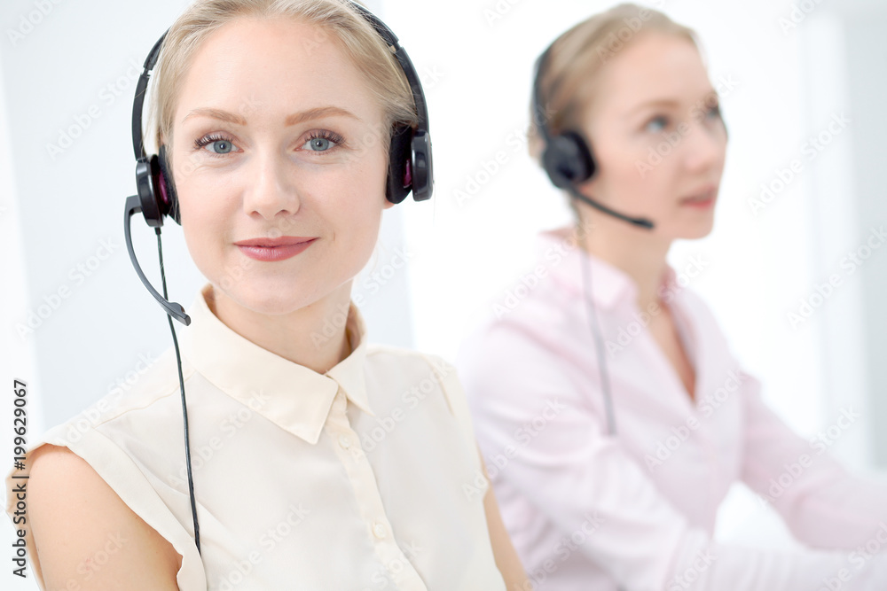 Image of bright call center. Focus on young beautiful woman in a headset Image of bright call center. Focus on young beautiful woman in a headset