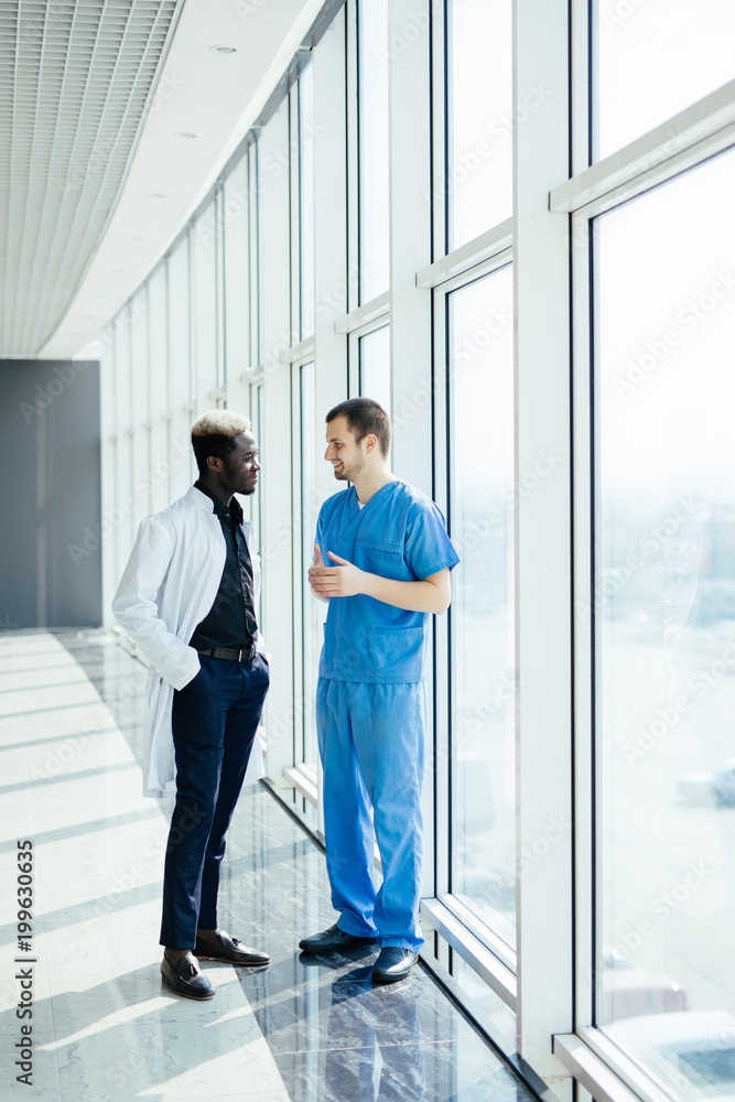 Mixed race two Doctors talking As They Walk Through Hospital Mixed race two Doctors talking As They Walk Through Hospital