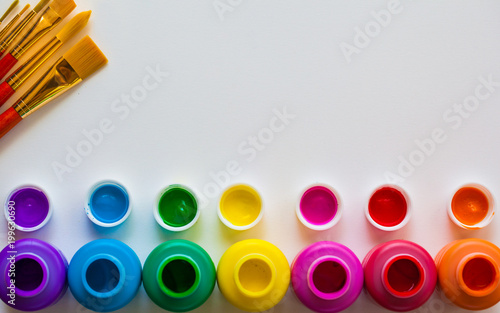 Colorful paint bottels and paint brushes on white background with copy space, top view/arts and crafts background concept