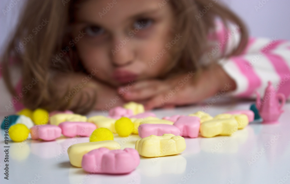Little girl, making faces, playing with candies; shallow depth of field Little girl, making faces, playing with candies; shallow depth of field