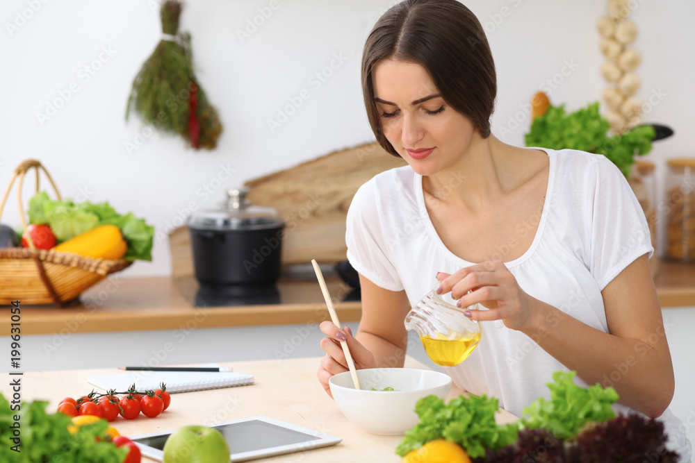 Beautiful Hispanic or latin american woman is holding wooden spoon while cooking in the kitchen. Beautiful Hispanic or latin american woman is holding wooden spoon while cooking in the kitchen.