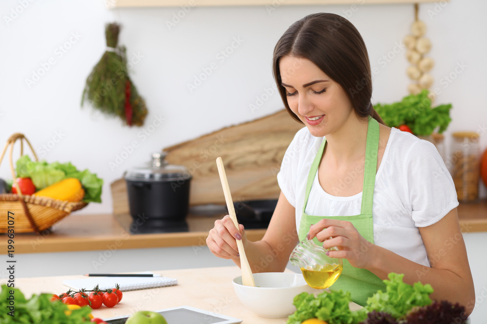 Beautiful Hispanic or latin american woman is holding wooden spoon while cooking in the kitchen. Beautiful Hispanic or latin american woman is holding wooden spoon while cooking in the kitchen.