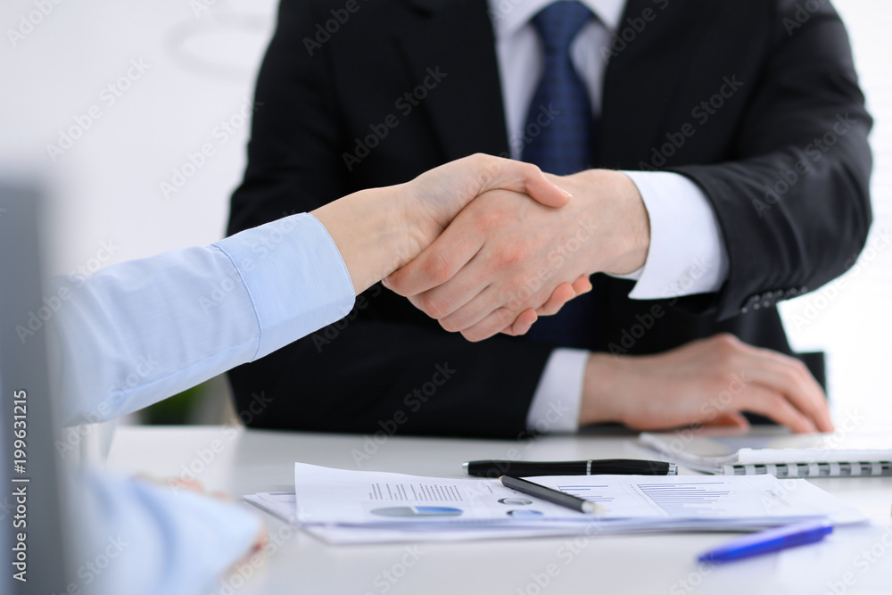 Close Up of unknown business people shaking hands while finishing up a meeting. Handshaking, agreement or success concept in people communication Close Up of unknown business people shaking hands while finishing up a meeting. Handshaking, agreement or success concept in people communication
