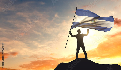 Nicaragua flag being waved by a man celebrating success at the top of a mountain. 3D Rendering