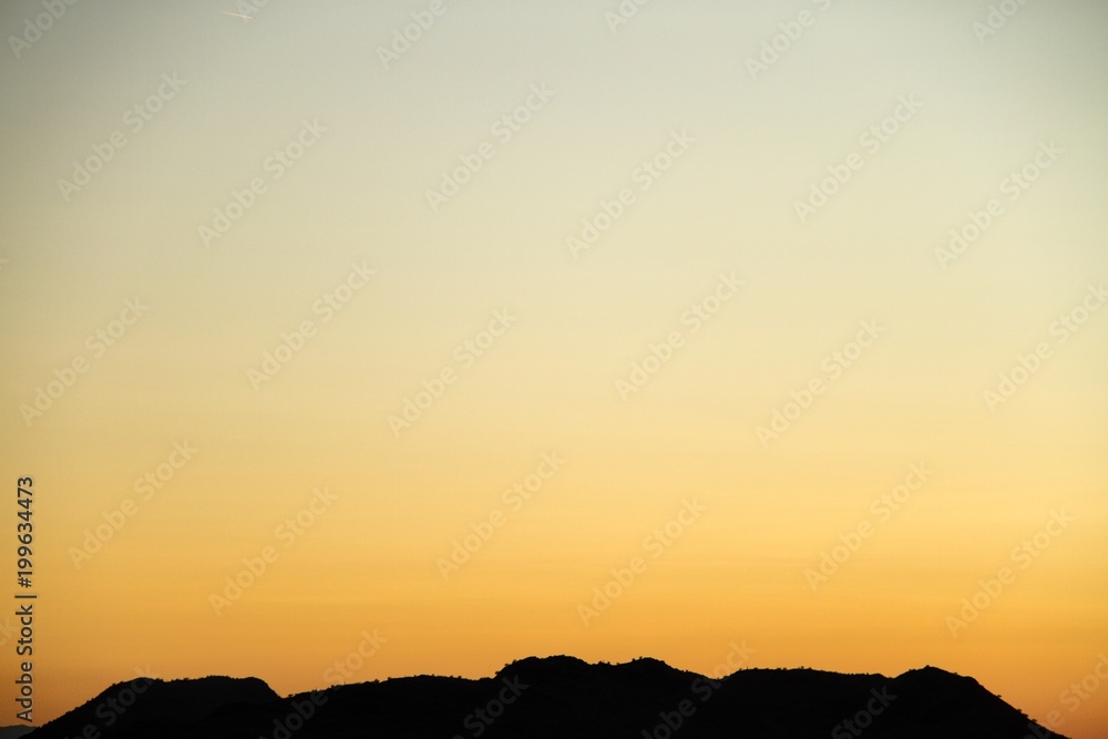A silhouette of a desert mountain with the sky providing copy space. A silhouette of a desert mountain with the sky providing copy space.