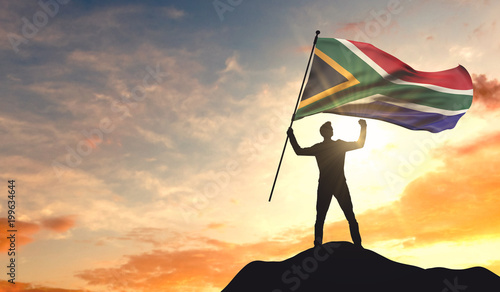 South Africa flag being waved by a man celebrating success at the top of a mountain. 3D Rendering photo